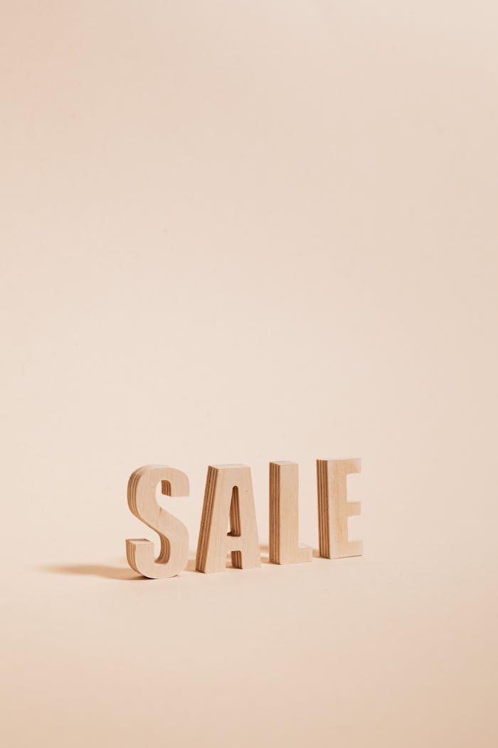 services-05 Wooden letters spelling SALE on a neutral beige background, perfect for promotions.